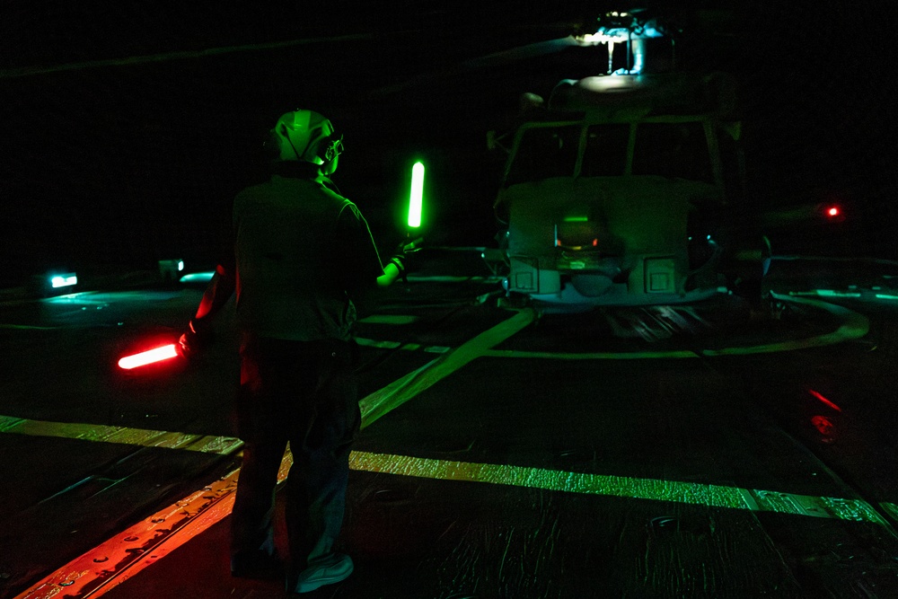 A U.S. Sailor Signals an MH-60R Sea Hawk Helicopter Attached to Helicopter Maritime Squadron 72