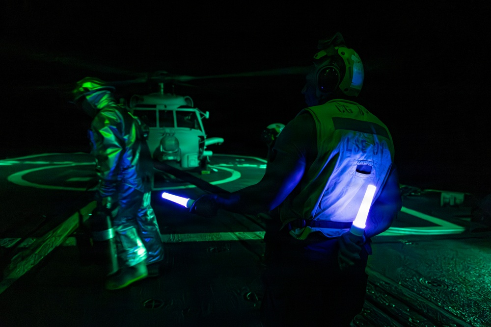 A U.S. Sailor Signals an MH-60R Sea Hawk, Attached to Helicopter Maritime Squadron 72