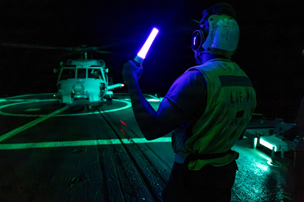 U.S. Sailor Signals an MH-60R Sea Hawk, Attached to Helicopter Maritime Squadron 72