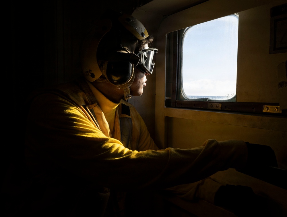 U.S. Sailor Prepares for the Arrival of an MH-60R Sea Hawk in the Hangar Bay