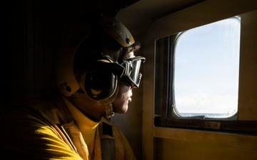 U.S. Sailor Prepares for the Arrival of an MH-60R Sea Hawk in the Hangar Bay