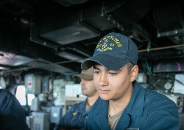 USS Mitscher (DDG 57) Sailor mans the helm in ship bridge