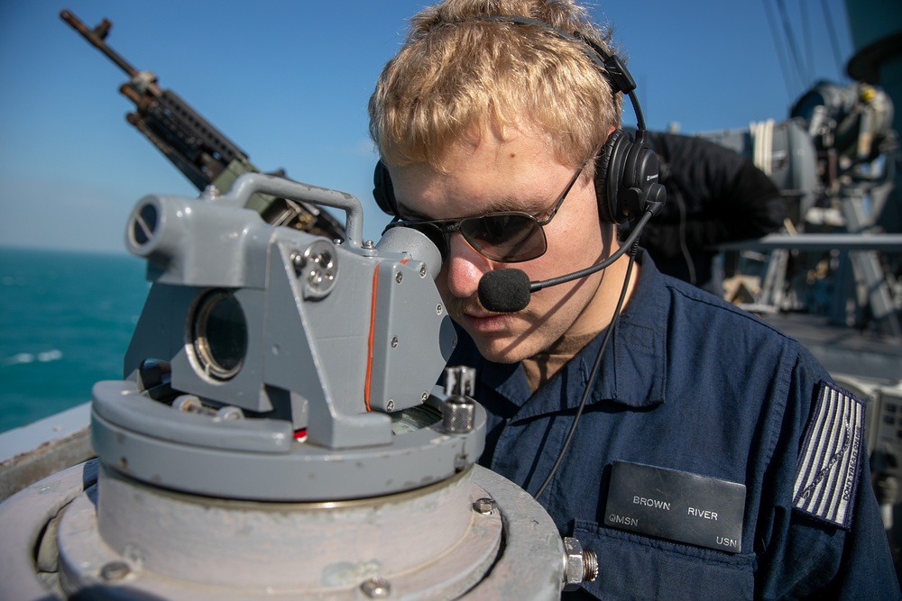 USS Mitscher (DDG 57) Sailor looks through compass on bridge wing