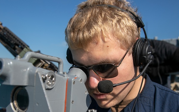 USS Mitscher (DDG 57) Sailor looks through compass on bridge wing