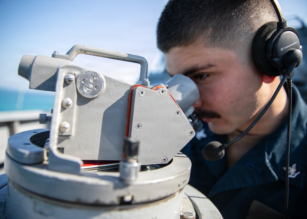 USS Mitscher (DDG 57) Sailor looks through compass on bridge wing