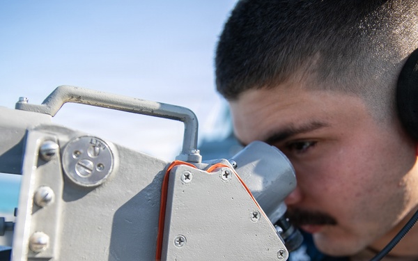 USS Mitscher (DDG 57) Sailor looks through compass on bridge wing
