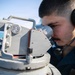 USS Mitscher (DDG 57) Sailor looks through compass on bridge wing