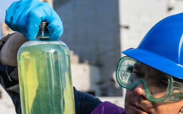 USS Mitscher (DDG 57) Sailor inspects fuel sample during RAS with USNS Carl Brashear (T-AKE 7)
