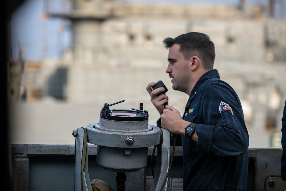 USS Mitscher (DDG 57) junior officer relays info on bridge wing during RAS with USNS Carl Brashear (T-AKE 7)