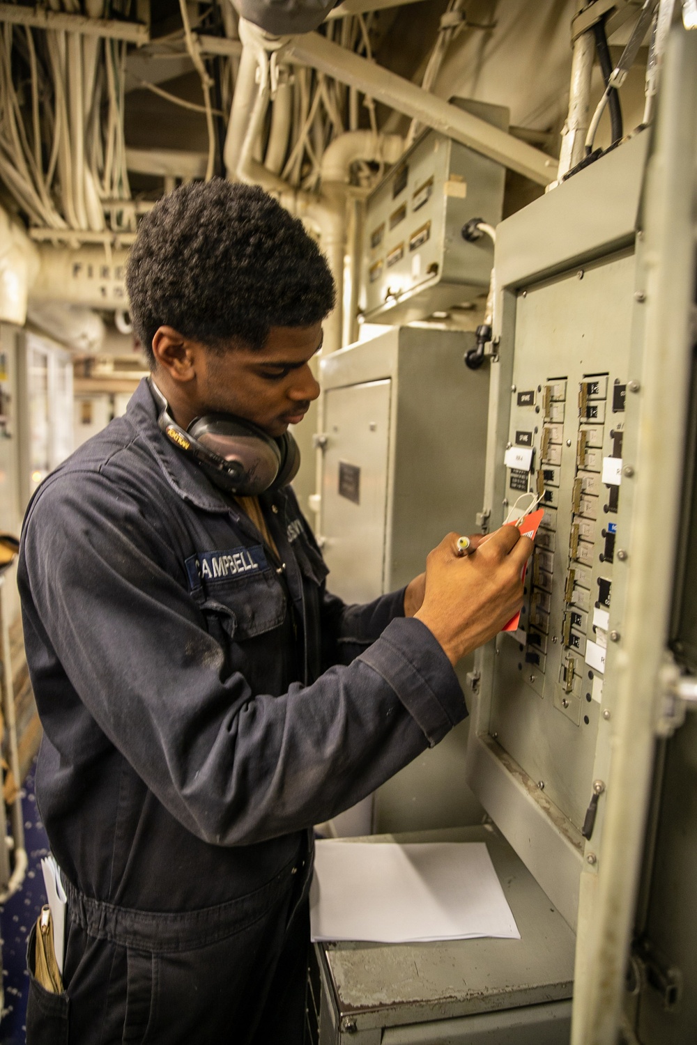 USS Mitscher (DDG 57) Sailor attaches safety tag to fuse box