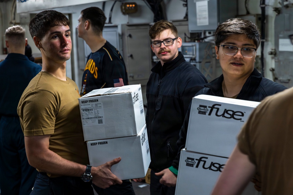 U.S. Navy sailors moving boxes during a working party aboard USS Abraham Lincoln in the Arabian Sea.