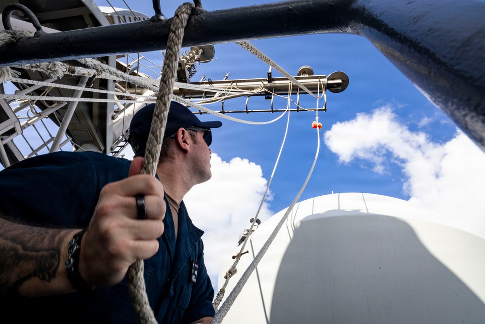 U.S. Sailor Hoists a Romeo Flag During a Replenishment-at-Sea