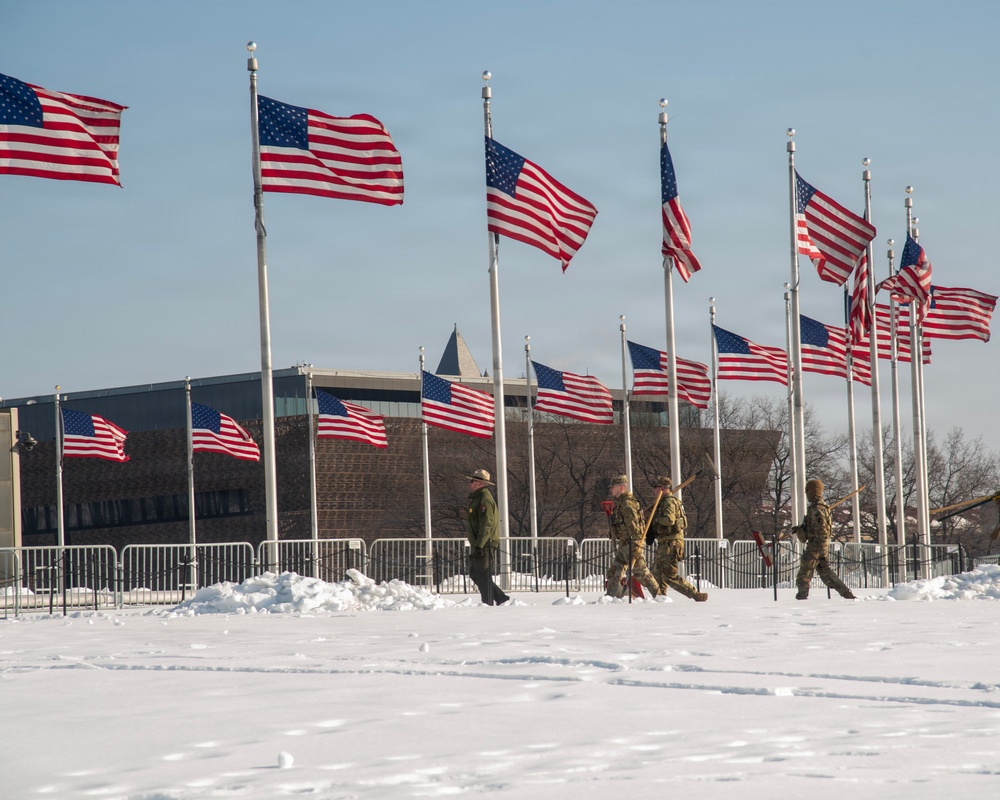 Service members clear snow at the Washington Monument