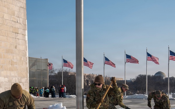 Service members clear snow at the Washington Monument