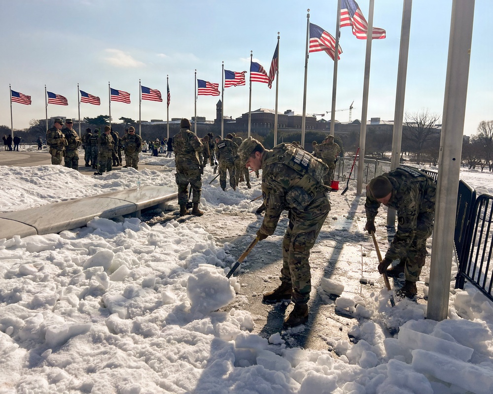 Service members clear snow at the Washington Monument