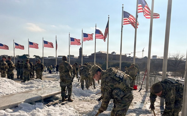 Service members clear snow at the Washington Monument