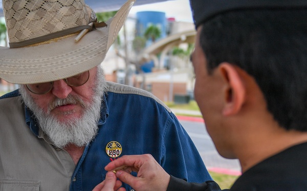 HM2 Ahn pins a Navy 250 pin on a civilian's shirt
