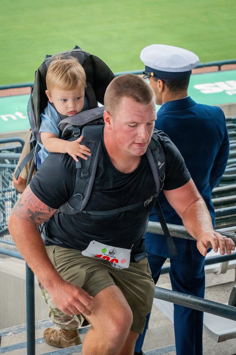 A Coast Guard member climbs while carrying his child