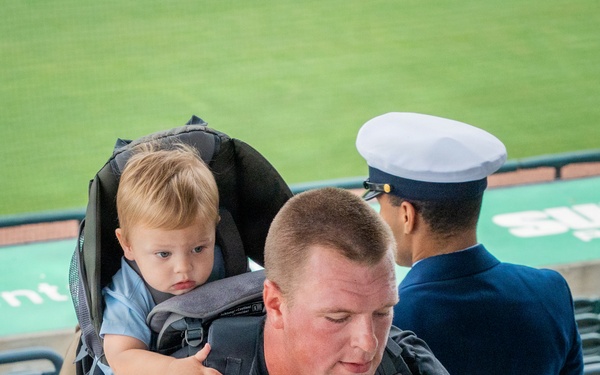 A Coast Guard member climbs while carrying his child
