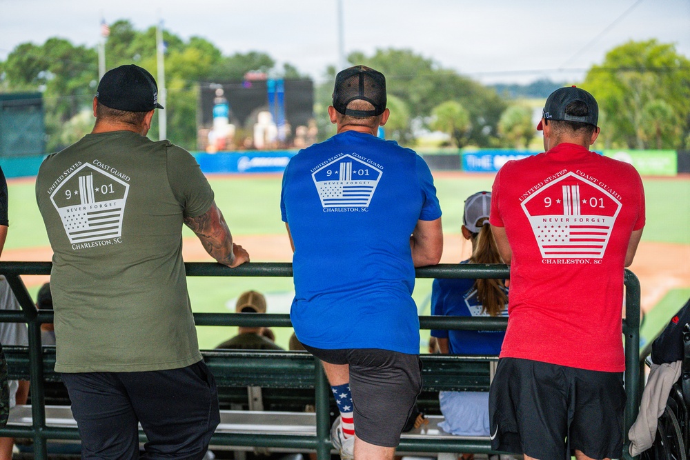 Three Coast Guard member looks on as scenes from 9/11 play on the center field screen.