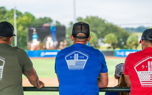 Three Coast Guard member looks on as scenes from 9/11 play on the center field screen.