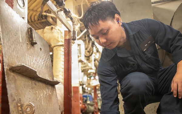 USS Mitscher (DDG 57) Sailor inspects valve in main machinery room