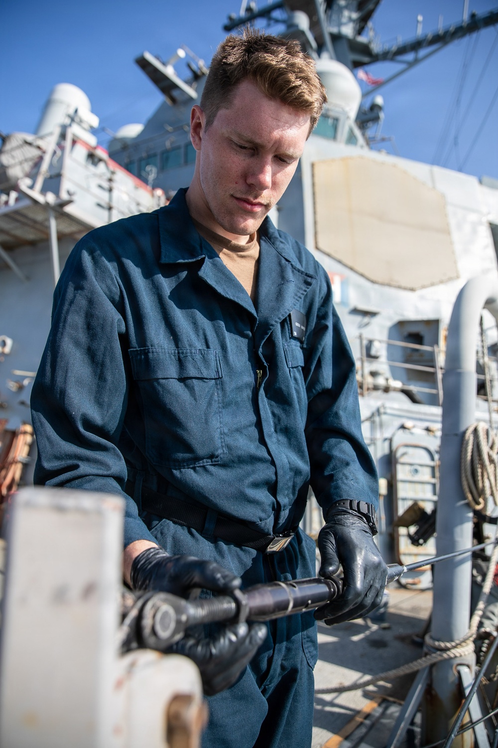USS Mitscher (DDG 57) Sailor installs safety line on ship foc'sle