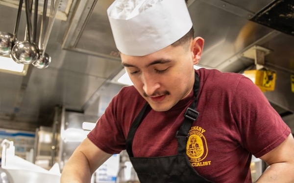 USS Mitscher (DDG 57) Sailor prepares food in ship galley