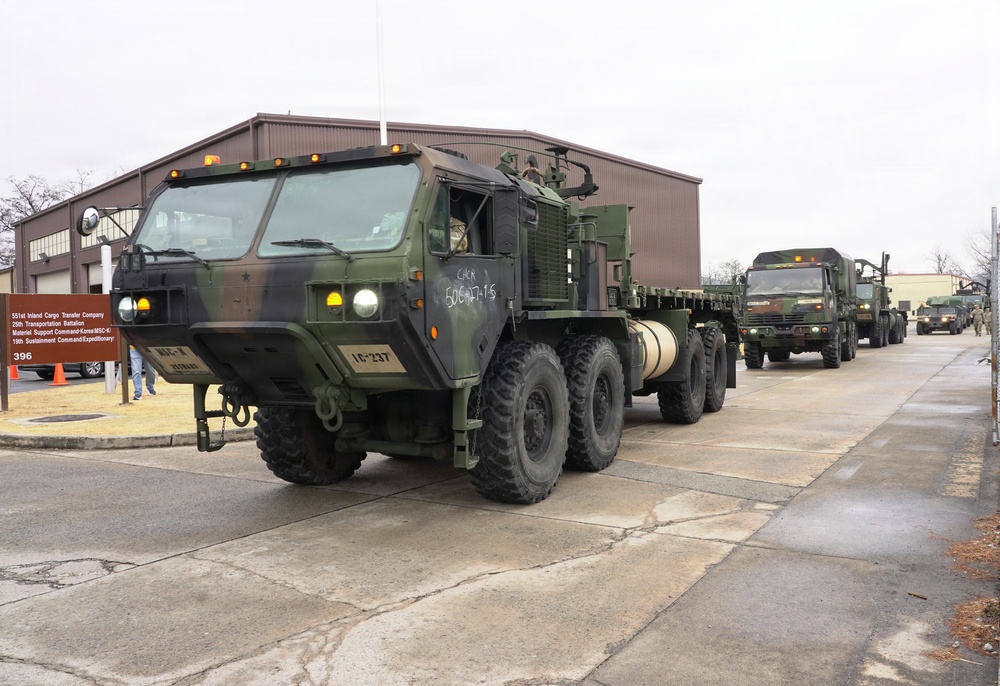 Convoy vehicles depart motor pool in coordinated tactical movement