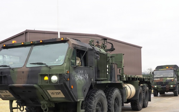 Convoy vehicles depart motor pool in coordinated tactical movement
