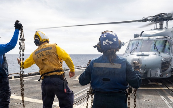 U.S. Sailors present chocks and chains to the pilots of an MH-60R Seahawk helicopter