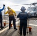 U.S. Sailors present chocks and chains to the pilots of an MH-60R Seahawk helicopter