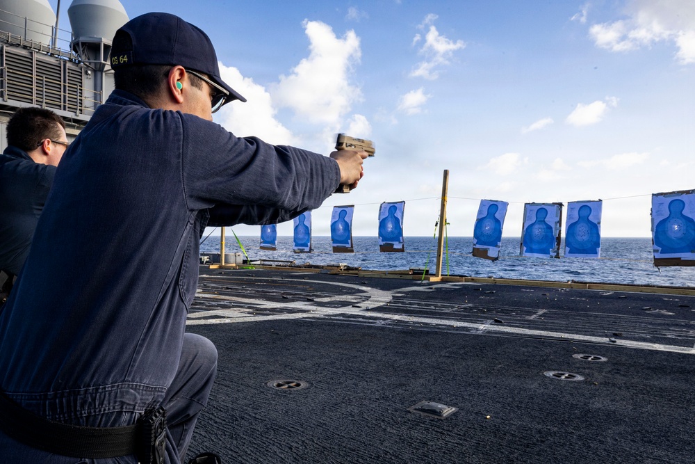 U.S. Sailor fires an M18 service pistol on the flight deck during a live-fire exercise