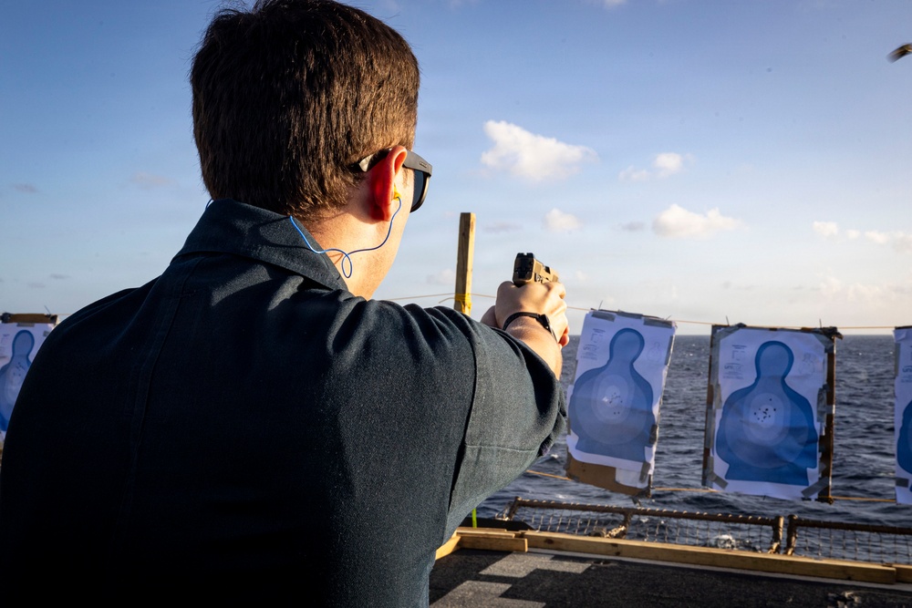 U.S. Sailor fires an M18 service pistol on the flight deck during a live-fire exercise