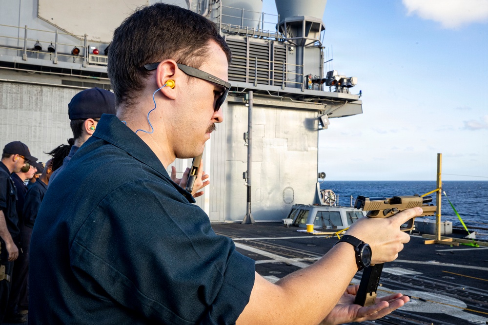 U.S. Sailor reloads an M18 pistol on the flight deck during a live-fire exercise