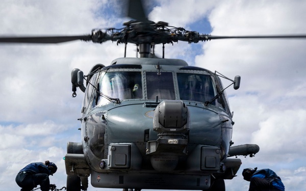 U.S. Sailors chock and chain an MH-60R Seahawk helicopter on the flight deck