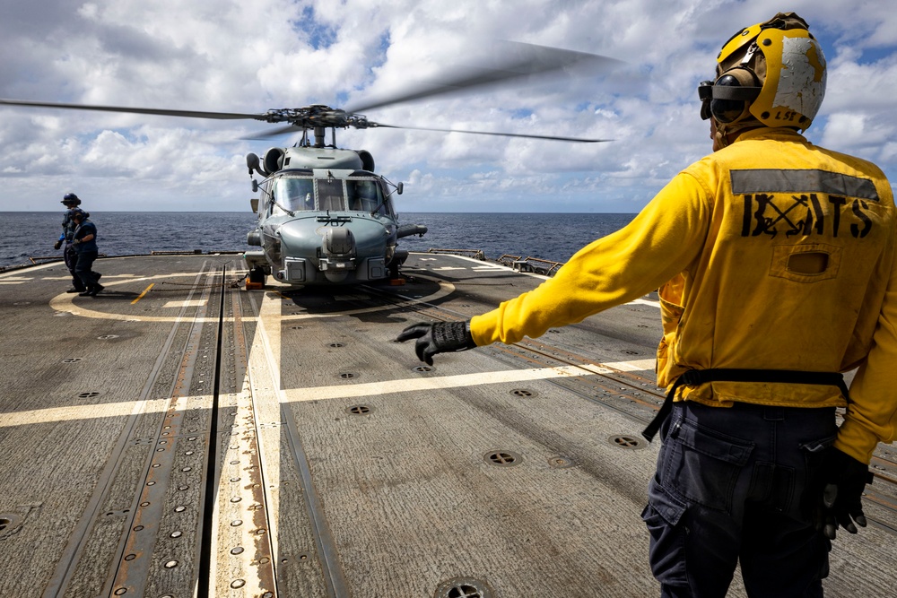 U.S. Sailor signals flight deck crew to move away from an MH-60R Seahawk helicopter