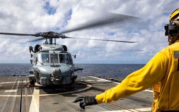 U.S. Sailor signals flight deck crew to move away from an MH-60R Seahawk helicopter