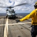 U.S. Sailor signals flight deck crew to move away from an MH-60R Seahawk helicopter