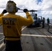 U.S. Sailor signals to flight deck crew near an MH-60R Seahawk helicopter on the flight deck