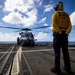 U.S. Sailor waits to signal an MH-60R Seahawk helicopter to lift off from the flight deck