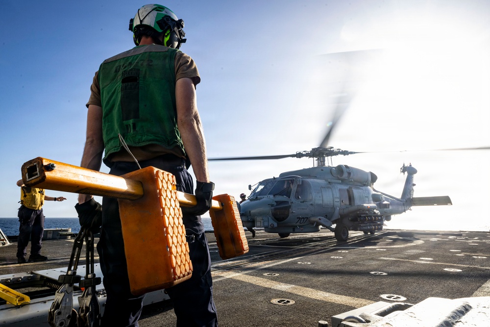 U.S. Sailors, assigned to the Iwo Jima Amphibious Ready Group, prepare to chock and chain an MH-60R