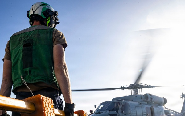 U.S. Sailors, assigned to the Iwo Jima Amphibious Ready Group, prepare to chock and chain an MH-60R