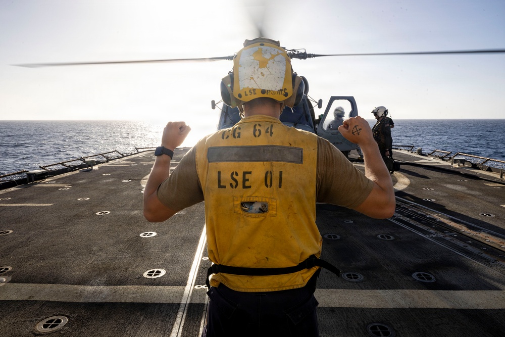 U.S. Sailor, assigned to the Iwo Jima Amphibious Ready Group, signals to an MH-60R Seahawk helicopter