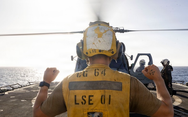 U.S. Sailor, assigned to the Iwo Jima Amphibious Ready Group, signals to an MH-60R Seahawk helicopter