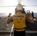 U.S. Sailor, assigned to the Iwo Jima Amphibious Ready Group, signals to an MH-60R Seahawk helicopter