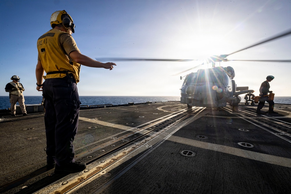 U.S. Sailor, assigned to the Iwo Jima Amphibious Ready Group, signals Sailors to remove chocks and chains