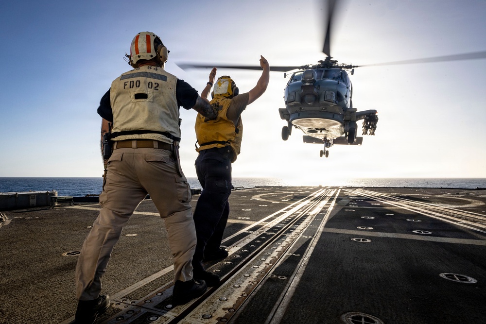 U.S. Sailor, assigned to the Iwo Jima Amphibious Ready Group, signals to an MH-60R Seahawk helicopter on the flight deck
