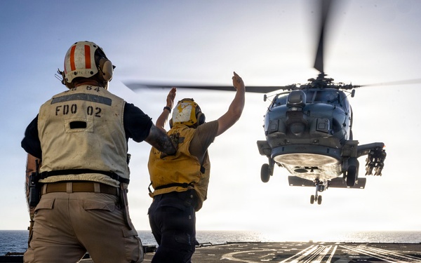 U.S. Sailor, assigned to the Iwo Jima Amphibious Ready Group, signals to an MH-60R Seahawk helicopter on the flight deck