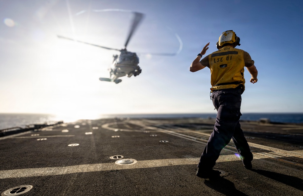 U.S. Sailor, assigned to the Iwo Jima Amphibious Ready Group, signals to an MH-60R Seahawk helicopter on the flight deck